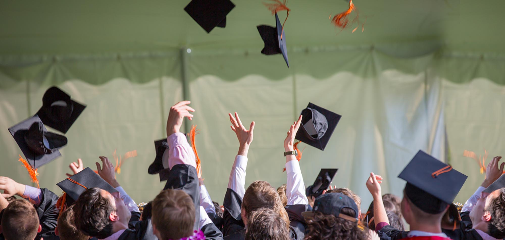 A large group graduating students throwing their caps in the air